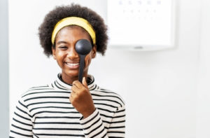 A young girl holding an occluder to her eye while performing vision tests