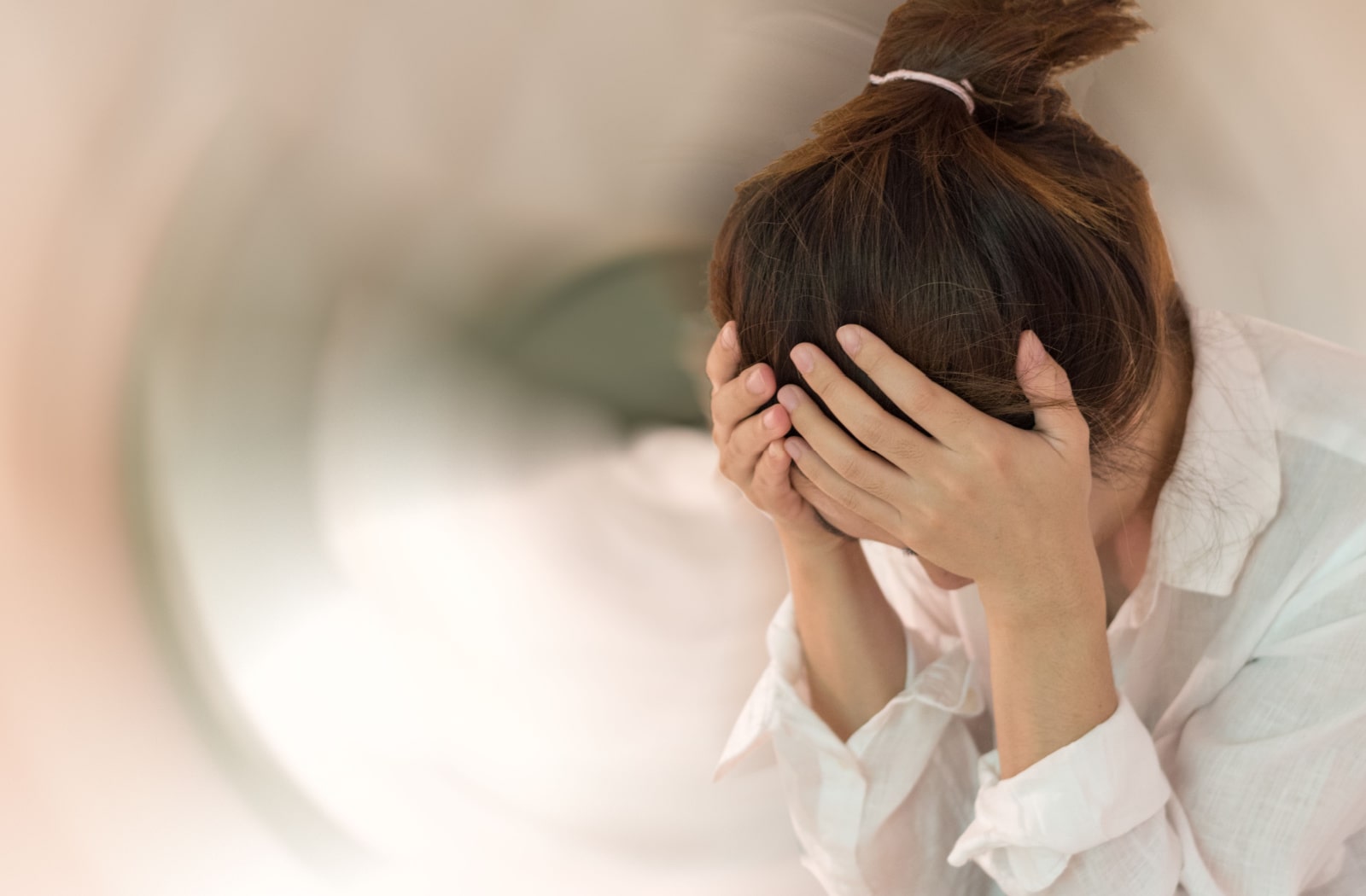 A woman putting her head in her hands as she deals with dizziness due to vision issues