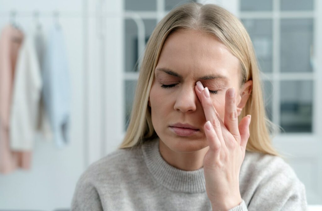 A woman rubbing the side of her eye due to dry eye pain