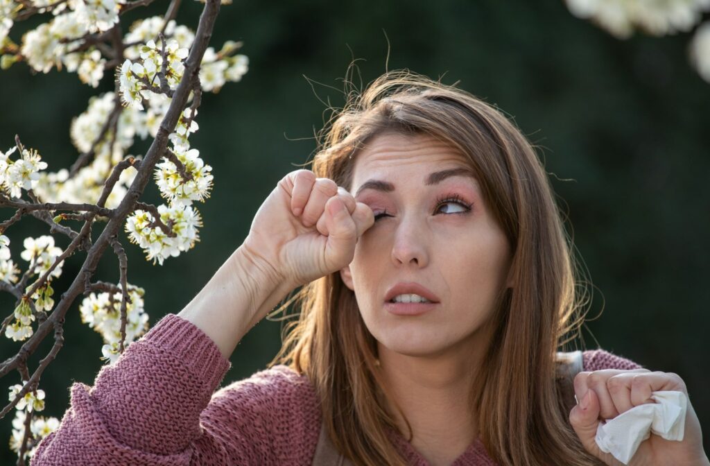 A woman, who is possibly experiencing an allergic reaction from a plant, rubbing her eyes.