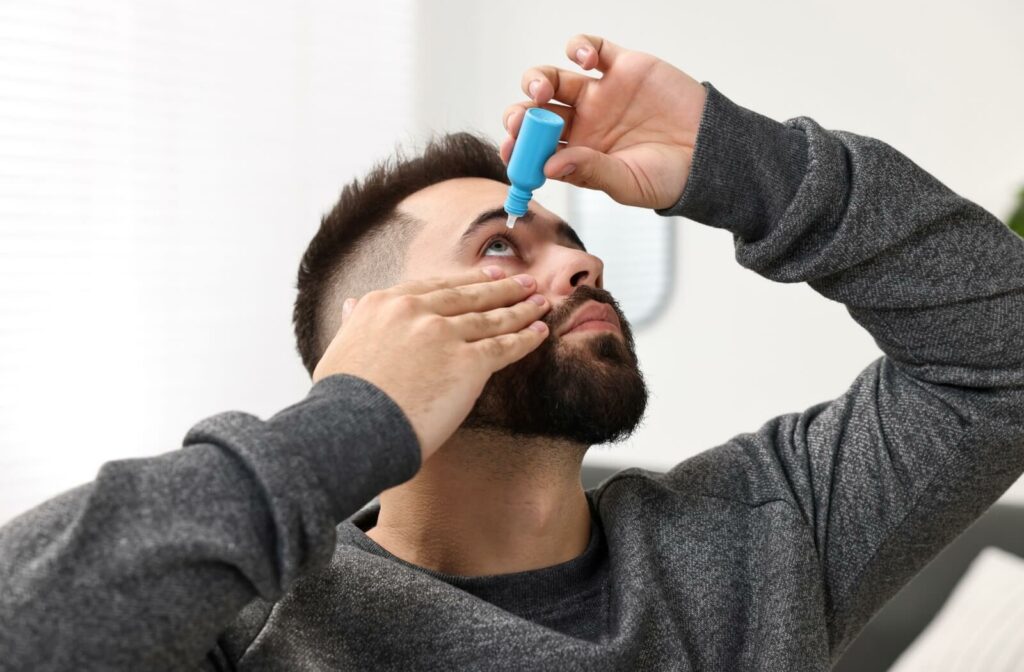 A man tilts his head back and pulls down his eyelid to apply eye drops for dry eye relief