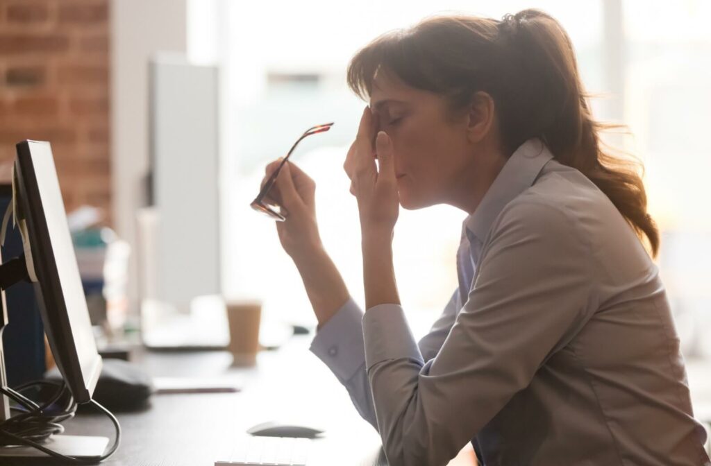 A woman working at her computer frustrated with her worsening myopia symptoms