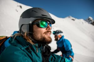 A person on a mountain wearing UV-protective sunglasses on a bright, sunny, winter day.