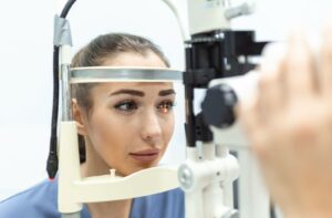 Woman undergoing a slit lamp eye exam at an optometry clinic, with focused lighting on her pupil to check for signs of diabetic eye conditions.