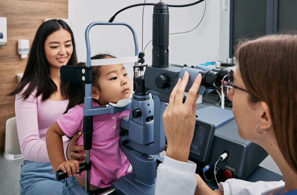 A child sitting on their parent's lap as an optometrists examines the child's eyes.