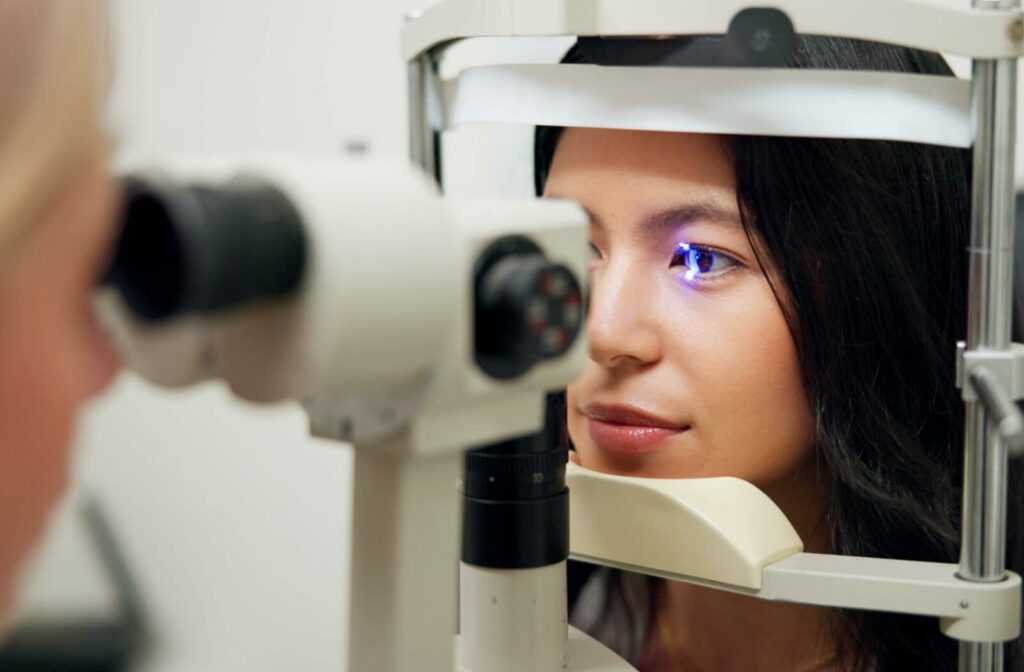 Close-up of a patient receiving a slit lamp examination during a comprehensive eye exam, with a blue diagnostic light illuminating the eye.