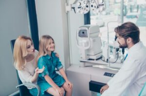 Optometrist consulting with a mother and young daughter during a children’s eye exam in a modern clinic.
